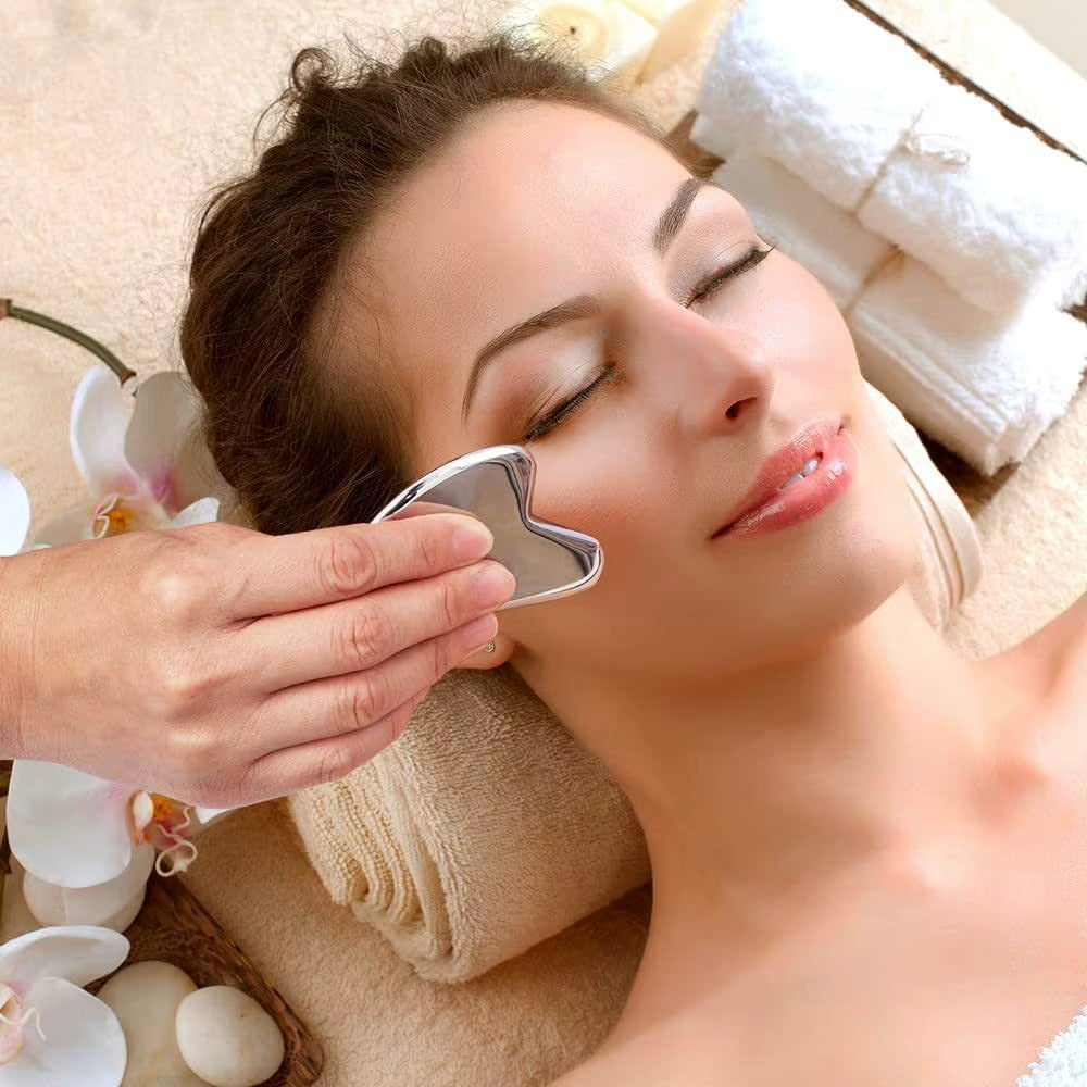 Woman using SkinSculpt™ stainless steel Gua Sha tool on her face to promote circulation and reduce puffiness